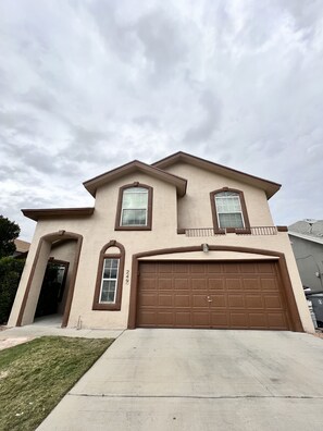 A two-story house with a brown garage door, a front entrance, and a small front yard.