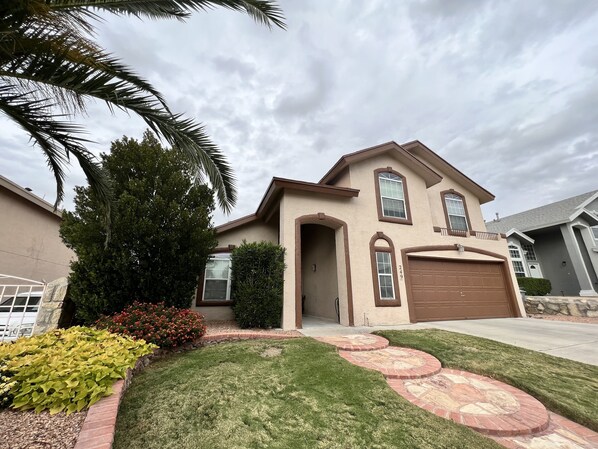 A two-story house with a beige exterior, a brown garage door, and a number '249' on the front.