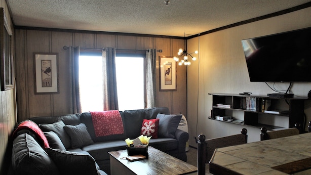 A living room with a sofa, coffee table, and a flat-screen TV mounted on the wall. - Slopeside ski in/out 1 bedroom condo with parking on site! (Snowshoe)