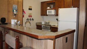 A kitchen with wooden cabinets, a microwave, a refrigerator, a stove, and a sink. - Slopeside ski in/out 1 bedroom condo with parking on site! (Snowshoe)
