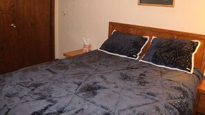 A bedroom with a dark blue quilted bedspread, a wooden headboard, and a framed picture on the wall. - Slopeside ski in/out 1 bedroom condo with parking on site! (Snowshoe)