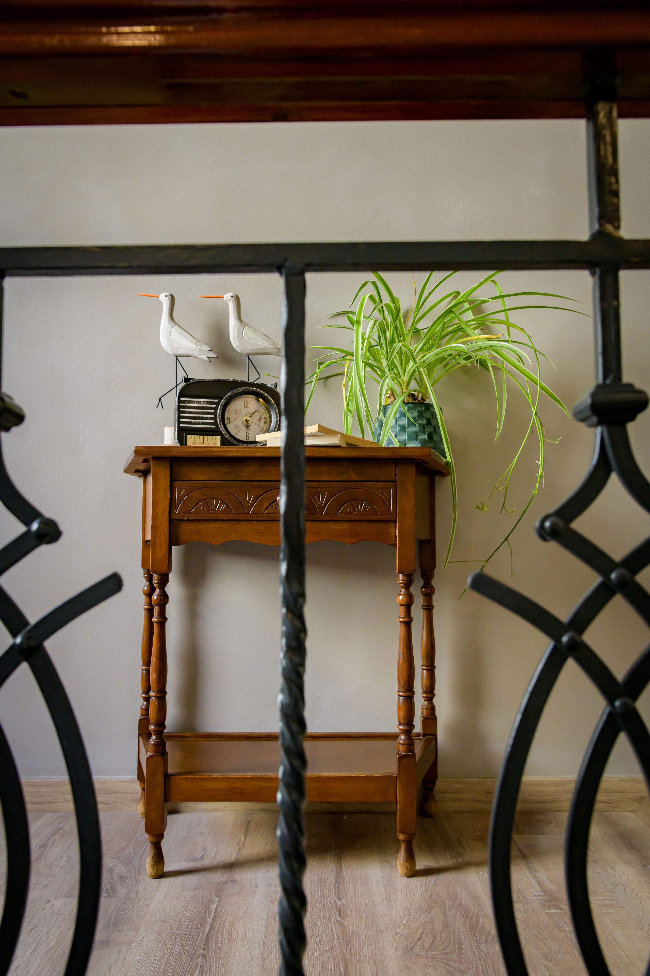 Una mesa de madera con una radio, dos figuritas de aves blancas y una planta en maceta.