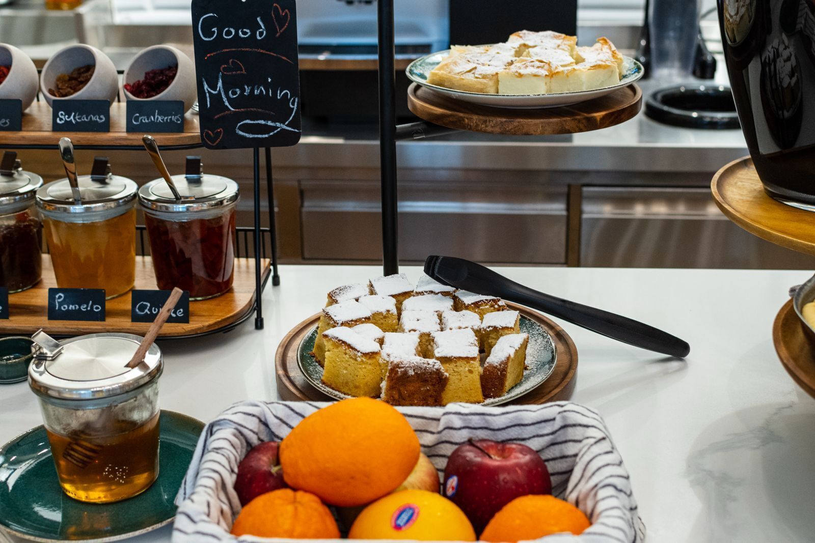 A breakfast buffet with various food items, including a cake, fruits, and condiments.