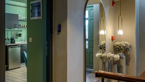 En modern inredning med trägolv, ett köksområde med diskmaskin och en hall som leder till ett badrum med spegel och blommor.