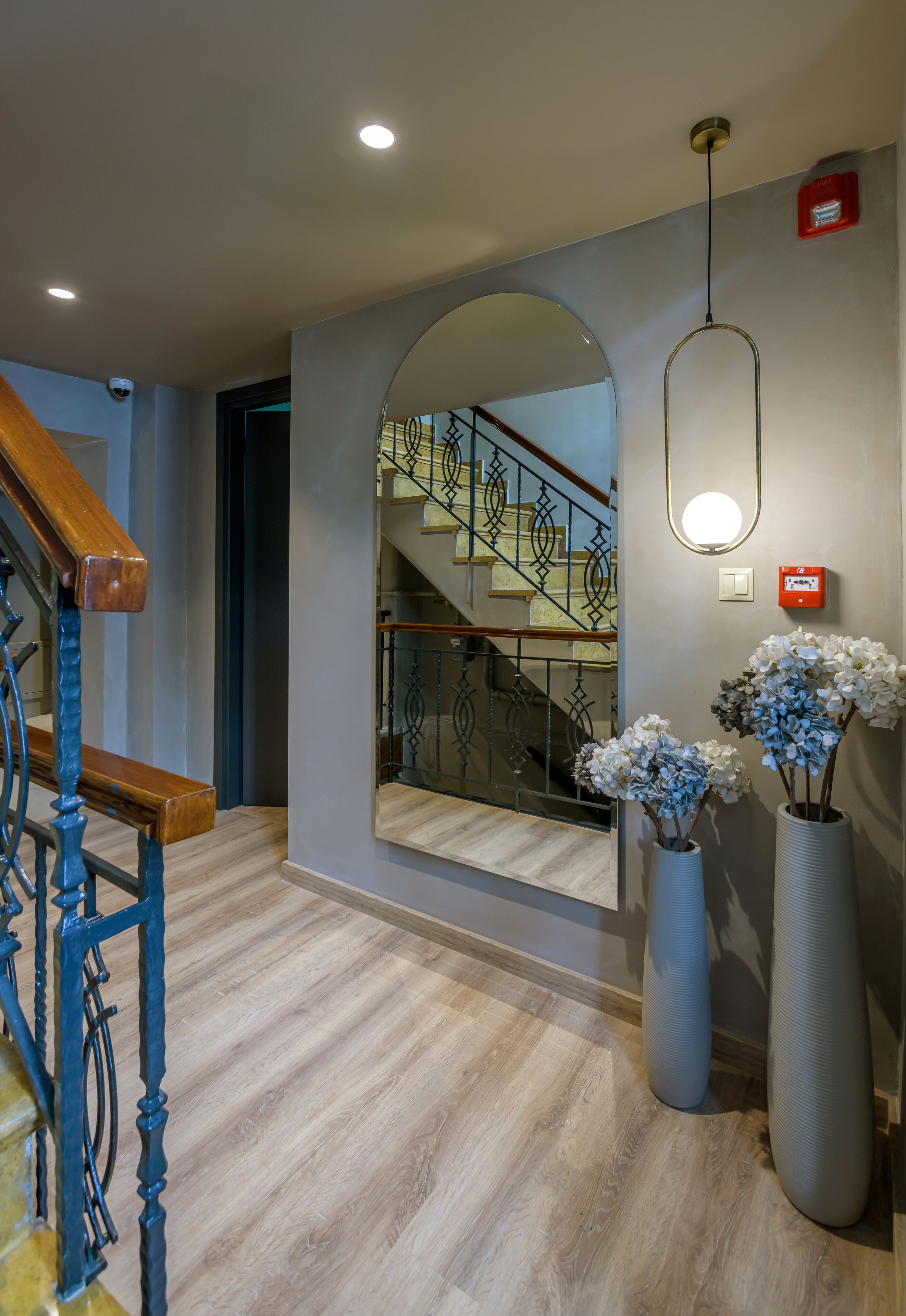 A modern interior with a wooden staircase, a large mirror, and decorative vases.