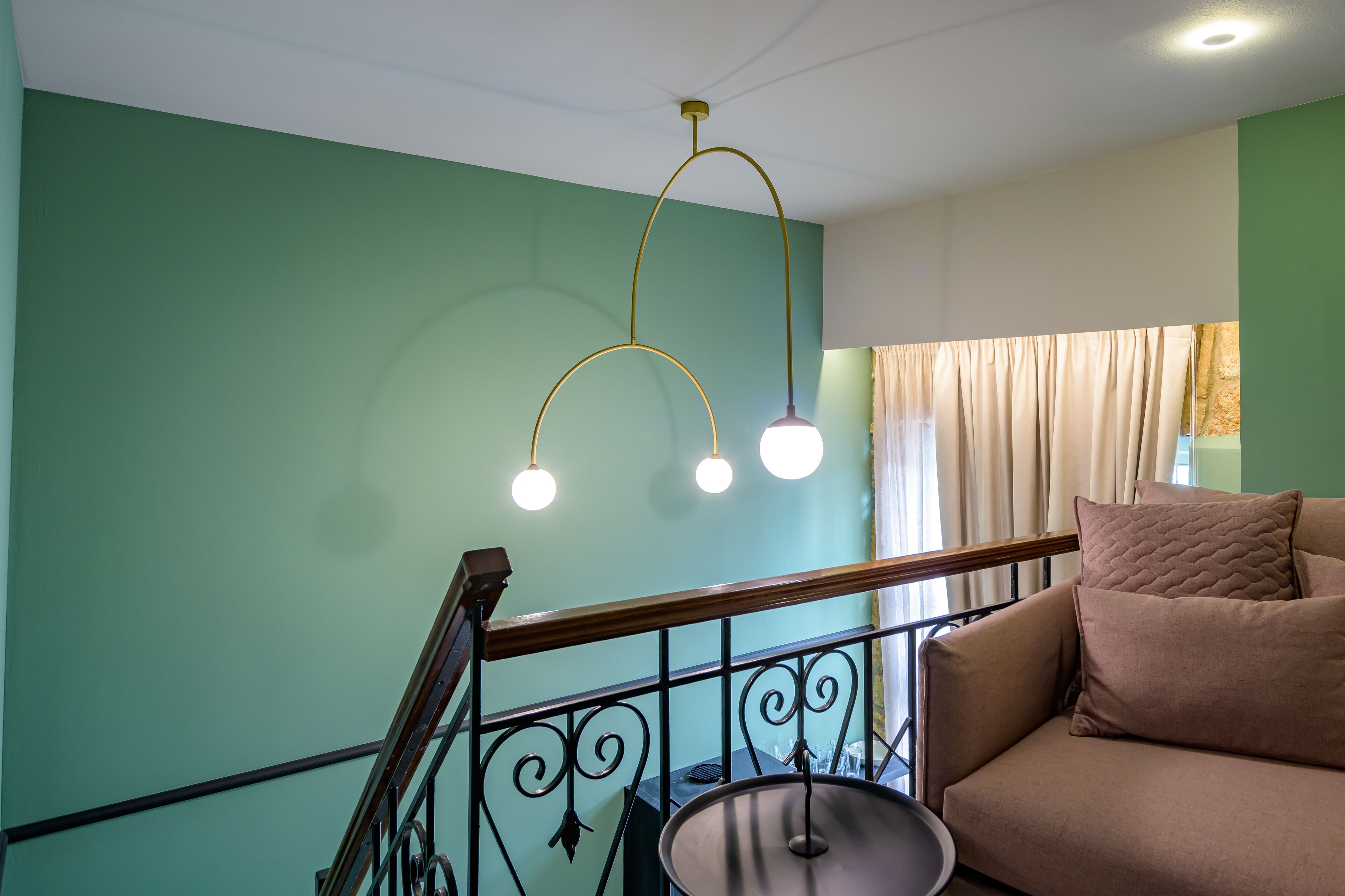 A staircase with a metal railing, a beige sofa with cushions, and a hanging light fixture.