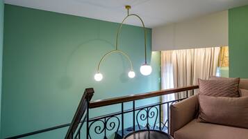 A staircase with a metal railing, a beige sofa with cushions, and a hanging light fixture.