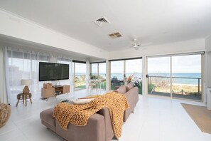Relax in this stylish living room with a large flat-screen TV, comfortable sofa, and ocean views from the balcony.