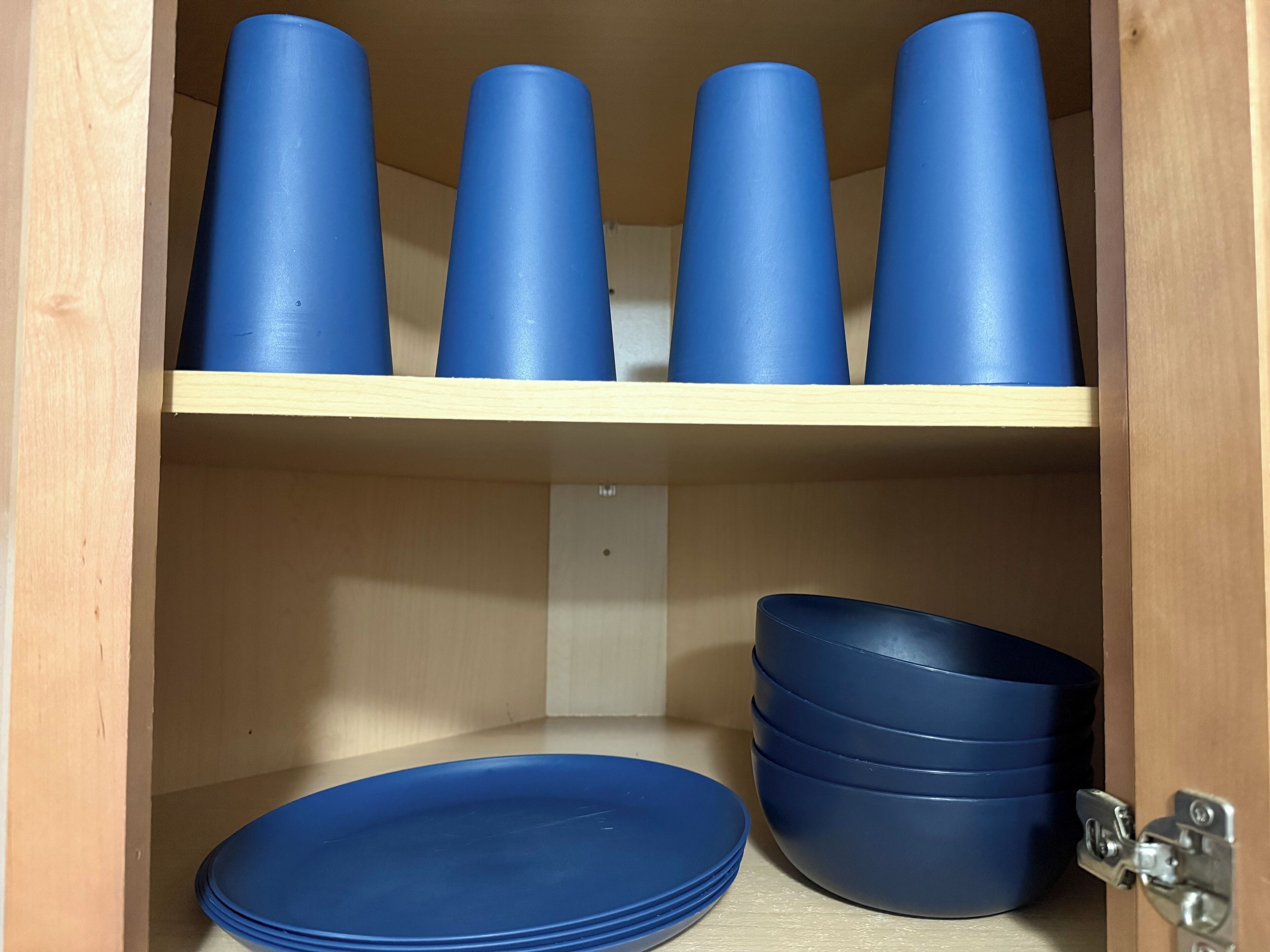 Ein Holzkabinent mit blauen Plastikbechern und -schüsseln.