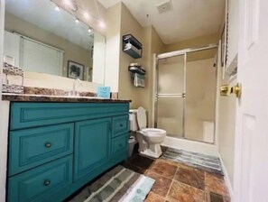 A bathroom with a teal vanity, a toilet, and a shower area. - Fayetteville, NC, close to I-295 and Fort Bragg (Fayetteville)