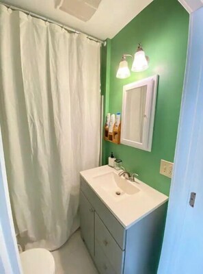 Un baño con lavamanos blanco, un espejo y una cortina de ducha.