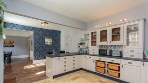 A modern kitchen with white cabinetry, a black countertop, and a tiled floor. - Orchard Lodge (Lytham St. Anne's)