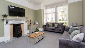 A living room with a fireplace, a flat-screen TV, a grey sofa, and a window with blinds. - Orchard Lodge (Lytham St. Anne's)