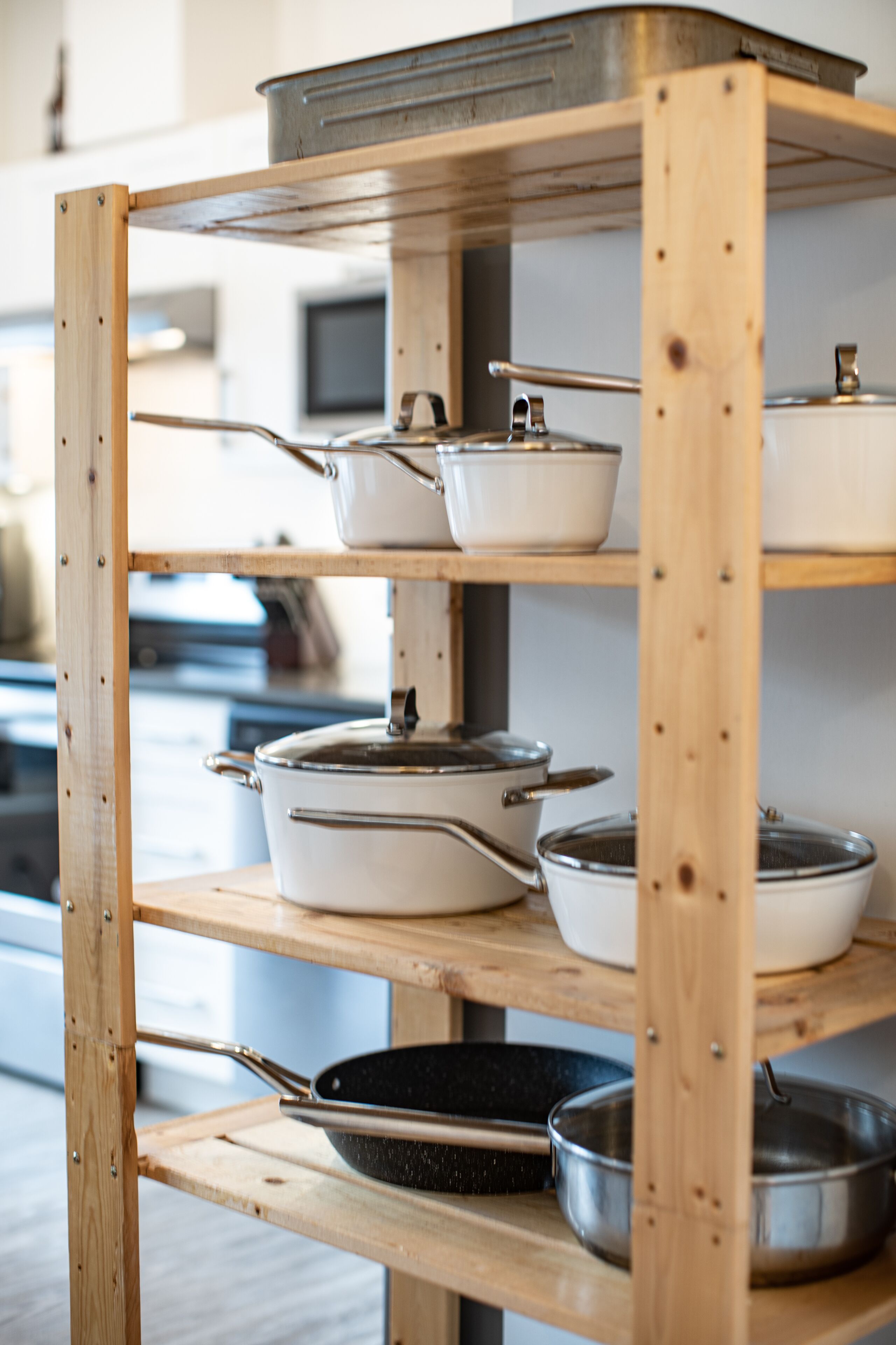 Un estante de madera con diferentes utensilios de cocina, incluyendo ollas, sartenes y una sartén.