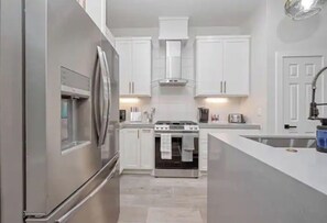 Modern kitchen with a central island, sink, and stainless steel appliances.