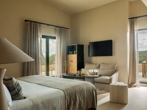 Habitación de hotel moderna con cama, escritorio, silla, televisor y balcón con cortinas.