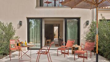 Un espace extérieur aménagé avec une table, des chaises et un parasol en osier.