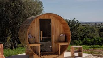 Une cabane en bois à la forme circulaire, comprenant un banc et une petite table, située dans un cadre naturel.