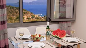 Mesa para dos con vistas al mar, una botella de vino, rebanadas de sandía y un bol de ensalada.