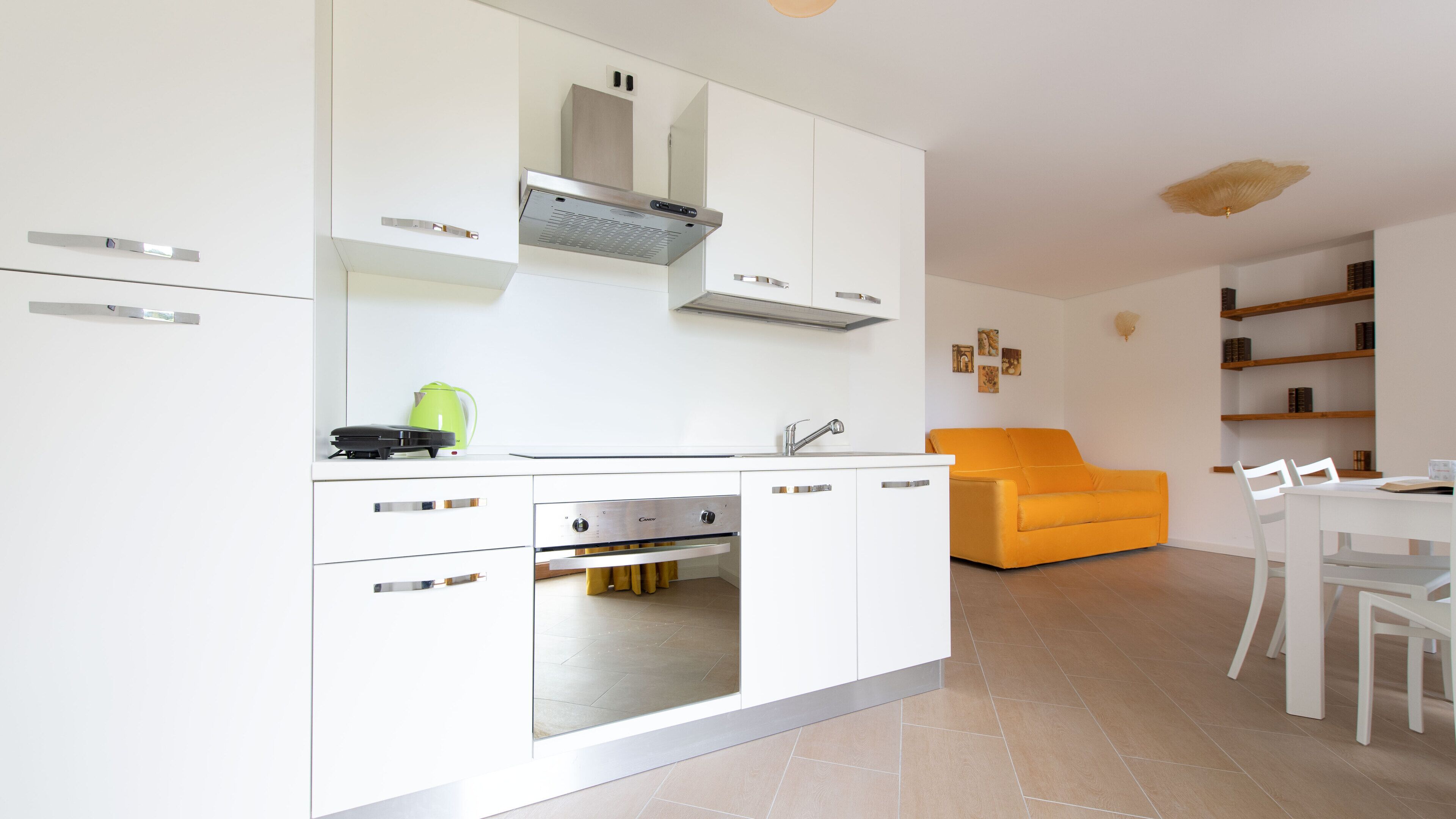 A modern kitchen with white cabinets, a built-in oven, and a coffee machine.