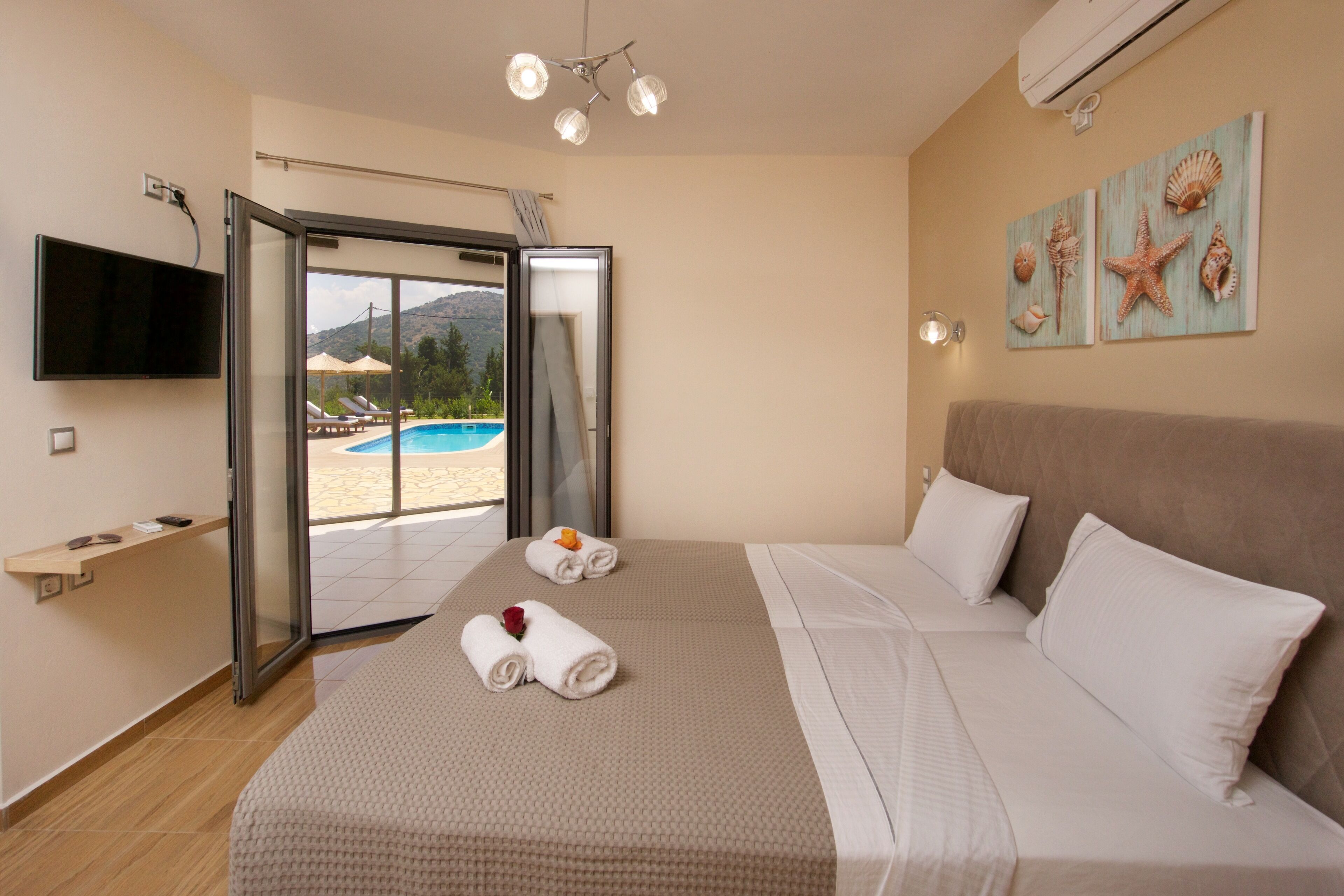 A hotel room with a bed, a TV, a pool view, and a beach view.