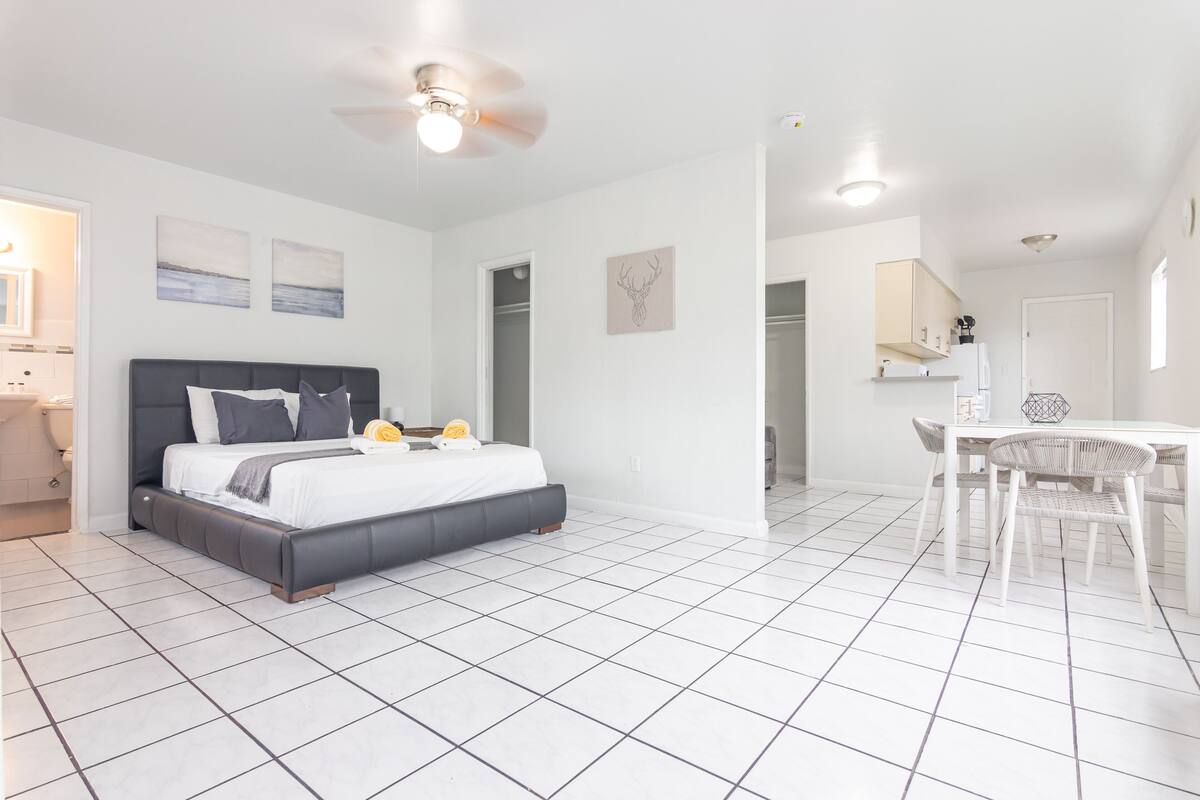 A modern bedroom with a bed, a ceiling fan, and a dining area with a table and chairs.