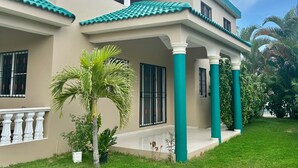 Une maison à deux étages dotée d’un porche abrité, d’un toit en tuiles et d’une pelouse bien entretenue.