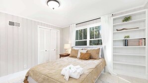 A neatly arranged bedroom with a bed, a nightstand, a window with curtains, a bookshelf, and a wardrobe. - Charm of SouthPark - 5 Bedrooms - 1 of a Kind Lot! (Charlotte)