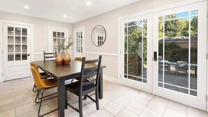A dining area with a table, chairs, and a view through large glass doors to an outdoor patio. - Charm of SouthPark - 5 Bedrooms - 1 of a Kind Lot! (Charlotte)