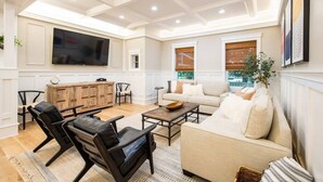 A spacious living room with a large flat-screen TV, a wooden cabinet, a beige sofa, and leather chairs. - The Green Monster: Indoor Slide+Bar+Near Camelback (Mount Pocono)