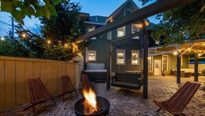 An outdoor patio with a fire pit, seating, and a covered area with lights. - The Green Monster: Indoor Slide+Bar+Near Camelback (Mount Pocono)