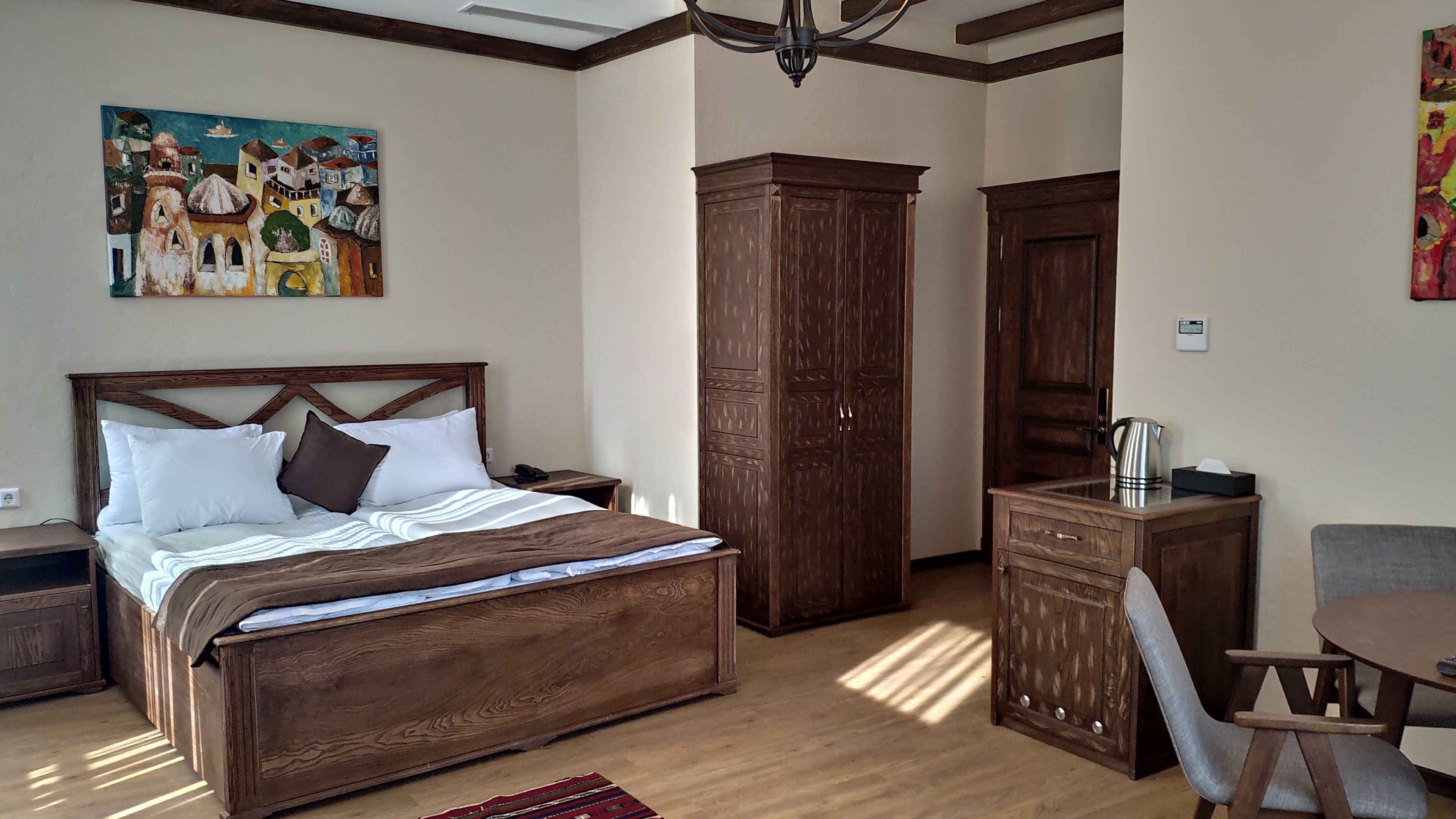 A bedroom with a large wooden bed, a nightstand, a wardrobe, a desk, and a chair.