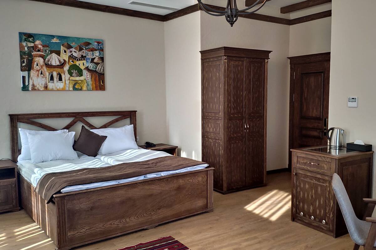 Un dormitorio con una cama de madera grande, una mesita de noche, un armario, un escritorio y una silla.