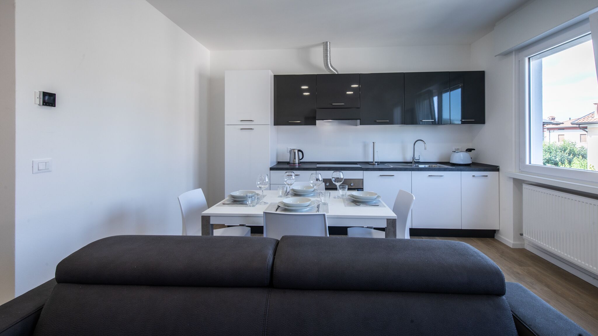 A modern kitchen with white cabinets, a black countertop, and a dining area with a table set for two.