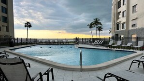 Una piscina con sillas de descanso y vistas al atardecer.