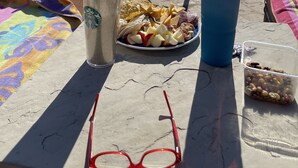 Ein Tisch am Pool mit einer Platte Snacks, zwei Getränken, einem Handtuch und Sonnenbrillen.