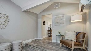 A modern living room with a high ceiling, a brown leather sofa, a round coffee table, and a lamp. - Institute Charm! King Studio w/ Kitchen & Smart TV (Colorado Springs)