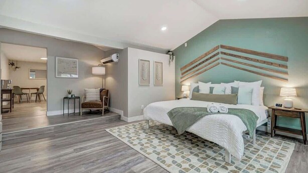 A bedroom with a bed, bedside tables, a desk, and chairs. - Institute Charm! King Studio w/ Kitchen & Smart TV (Colorado Springs)