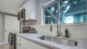 A kitchen with a granite countertop, stainless steel sink, and white cabinetry. - Institute Charm! King Studio w/ Kitchen & Smart TV (Colorado Springs)