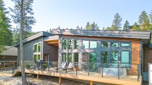 A modern house with a deck, large windows, and a wooden deck railing.