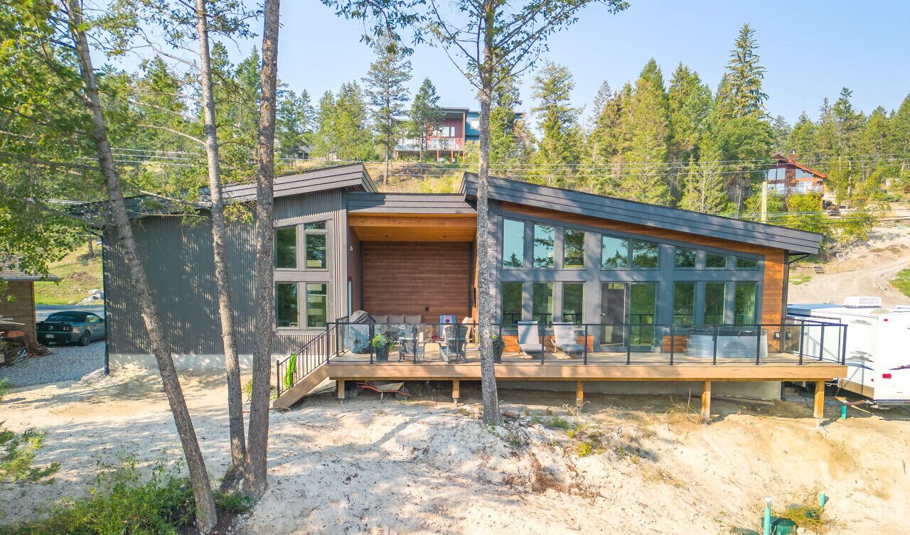 Une maison moderne dotée d’une grande baie vitrée, d’une terrasse et d’un garage.