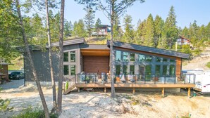 A modern house with a large glass window, a deck, and a garage.