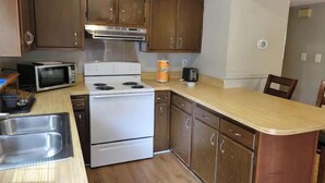 Une cuisine avec des meubles de rangement en bois, une cuisinière blanche, un four à micro-ondes et un grille-pain.