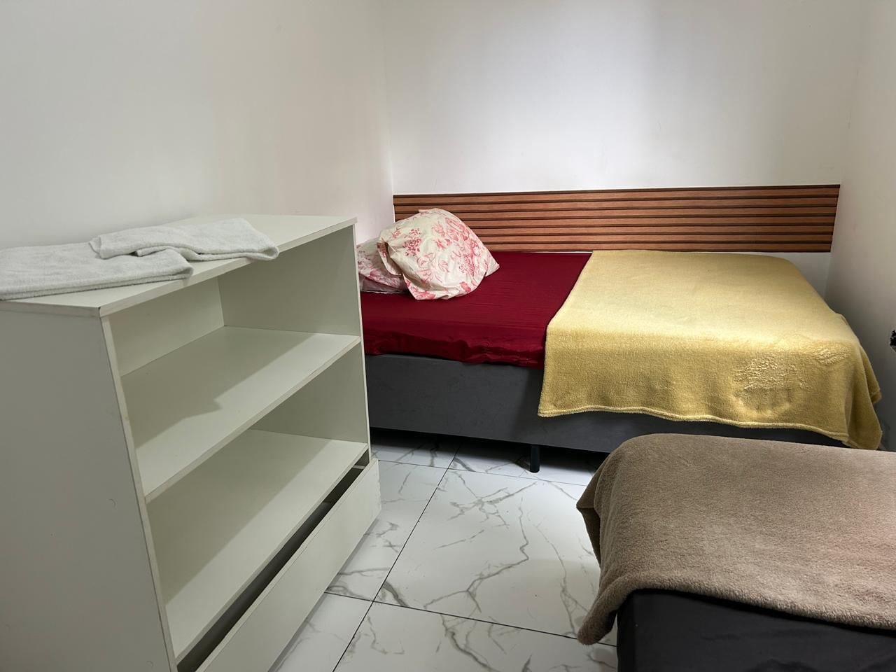 Un dormitorio con una cama, un armario y estanterías.