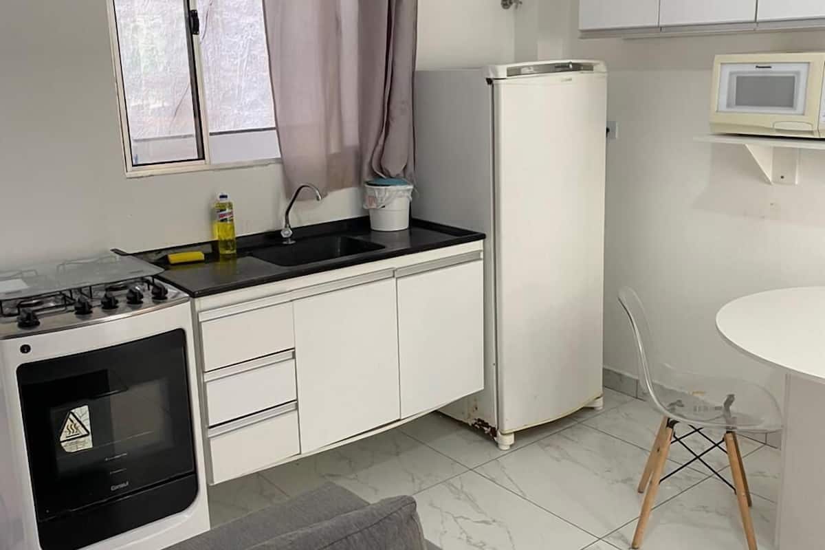 A compact kitchen with a stove, refrigerator, and microwave.