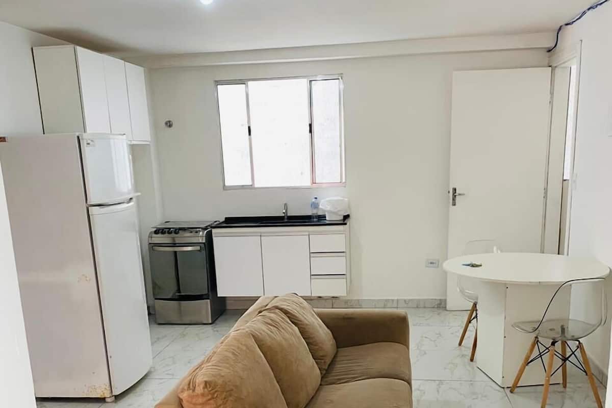 A compact living space with a sofa, kitchenette, and a dining area.