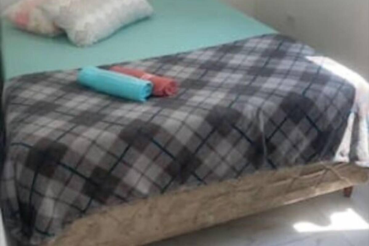 A small, simple room with a bed, a pillow, and a blanket.