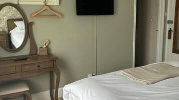 A bedroom with a bed, a dresser, a mirror, a television, and a door.