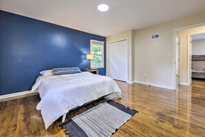 A bedroom with a bed, a nightstand, a lamp, a window, and a door. - NEW! Beautiful-Clean-Modern-Convenient-Accessible (Overland Park)