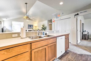 Kitchen features a central island with sink and dishwasher, surrounded by cabinetry and a countertop.